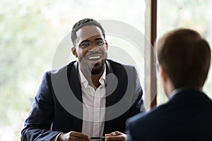 Smiling African American businessman talk with colleague at meeting