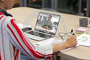 Smiling african american businessman video conferencing with female colleague through laptop