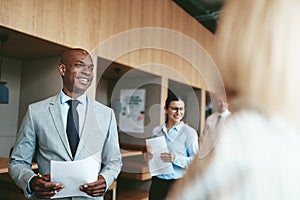 Smiling African American businessman walking with colleagues in