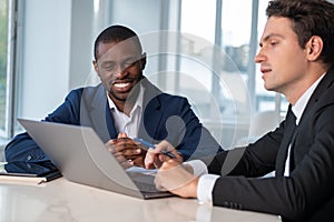 Smiling African American businessman wearing formal suit talking to colleague