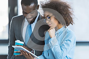 smiling african american businesspeople looking at tablet