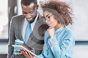 smiling african american businesspeople looking at tablet