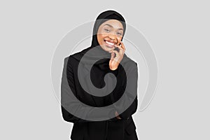 Smiling African American businesswoman in a hijab engaging in a phone conversation