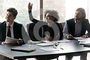Smiling African American businesswoman raising hand, asking question