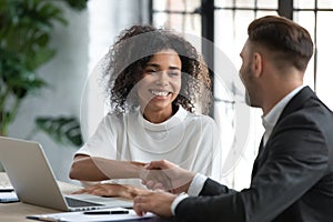 Smiling African American businesswoman shaking client hand at meeting