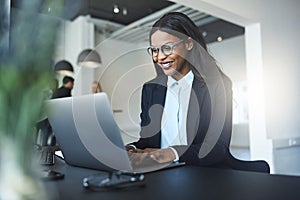 Smiling African American businesswoman using a laptop at her des