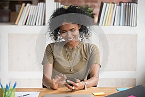 Smiling African American businesswoman using mobile device apps at work