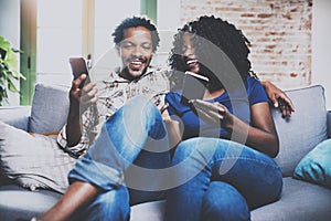 Smiling african american couple relaxing together on the sofa.Young black man and his girlfriend using mobile devices