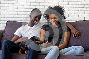 Smiling African American couple using phone, surfing internet