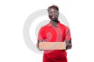 Smiling african american delivery man holding cardboard box and looking at camera isolated on white background
