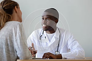 Smiling African American doctor talking to patient at visit photo