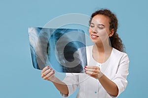 Smiling african american doctor woman in white medical gown hold X-ray of lungs, fluorography, roentgen isolated on blue