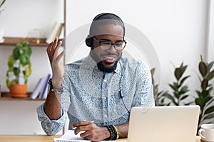 Smiling African American employee in headphones using laptop