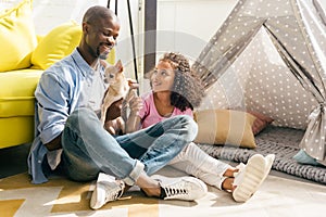 smiling african american family with chihuahua dog sitting on floor together