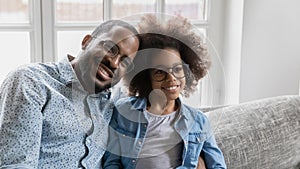 Smiling african american family in eyeglasses sitting on sofa.