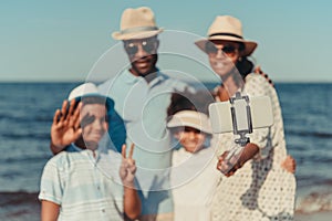 smiling african american family with two kids taking selfie with smartphone