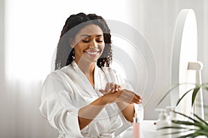 Smiling African American Female Using Moisturising Cream For Hands At Home