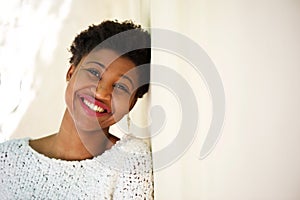 Smiling african american girl leaning against white wall
