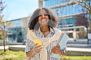 Smiling African American girl student walking in park using mobile phone.