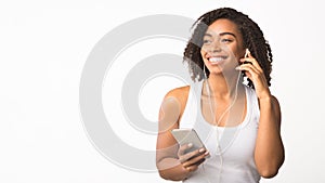 Smiling african american girl using phone for listening to music