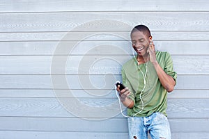 Smiling african american guy listening to music with earphones