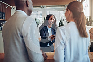 Smiling African American hotel concierge helping guests during c