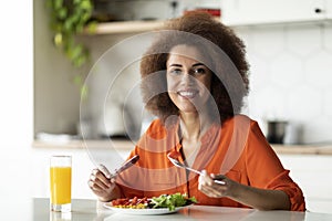 Smiling African American Lady Eating Breakfast Or Lunch At Table In Kitchen