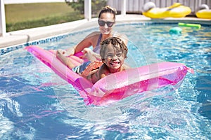 Smiling African American little boy playing in the swimming pool with an inflatable raft.