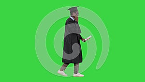 Smiling african american male student in graduation robe talking on the phone while walking on a Green Screen, Chroma