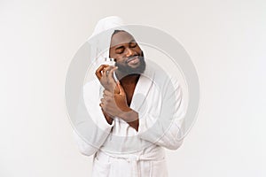 Smiling African American man applying cream on his face. Man& x27;s skin care concept