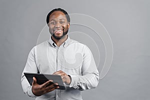 Smiling African-American man holding digital tablet isolated on grey