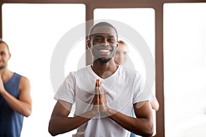 Smiling african-american man holding hands in namaste at group t