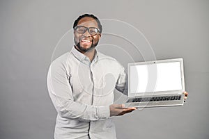 Smiling African-American man with laptop isolated on grey