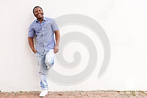 Smiling african american man leaning against white wall