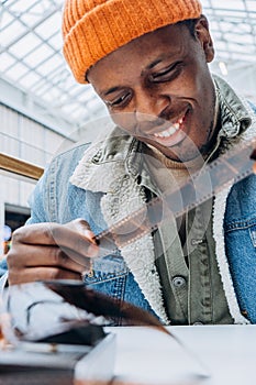 Smiling African-American man looks at photos on film in room