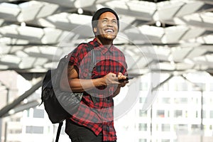 Smiling african american man with mobile phone and bag looking up