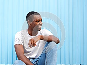 Smiling african american man sitting against blue background