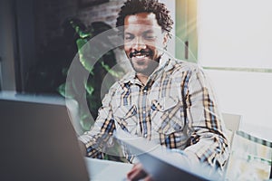 Smiling African American man using laptop while sitting in living room.Concept of young guy using Internet-enabled