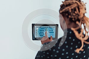 Smiling African American man using modern smart home system, controller on wall, positive young man switching