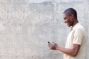 Smiling african american man walking and looking at cellphone