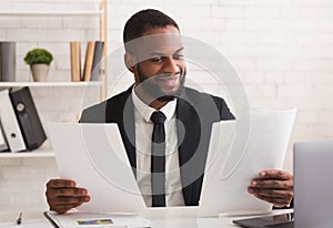 Smiling african american manager checking reports in modern office