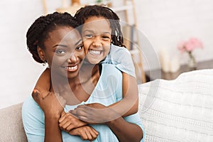 Smiling african american mom and daughter cuddling