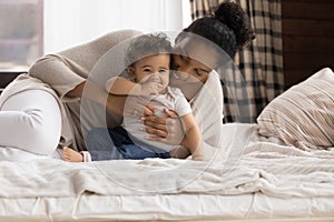 Smiling African American mother with baby lying in cozy bed