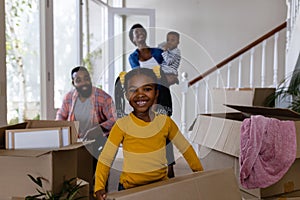 Smiling african american parents and children with boxes enjoying in new home