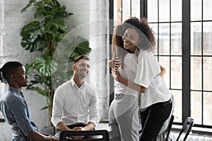 Smiling African American psychologist hugging patient at group therapy session