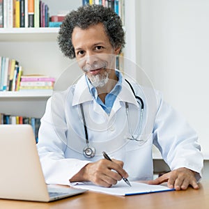 Smiling african american senior doctor working at desk