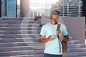 Smiling african american student looking at cellphone