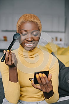 Smiling african american woman applying powder photo