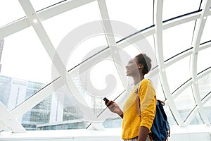 Smiling african american woman with bag and mobile phone at station