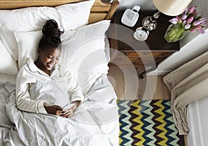 Smiling African American woman on bed using a cellphone